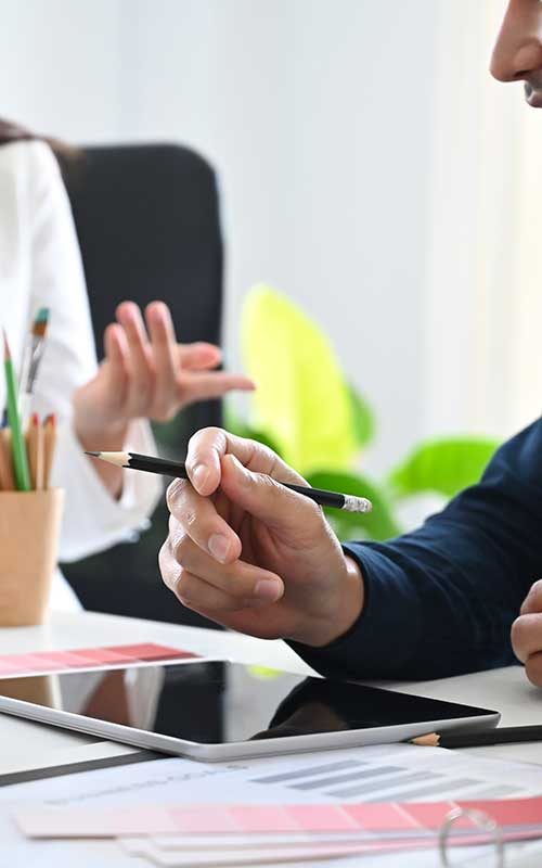 person holding pencil and tablet placed on the table